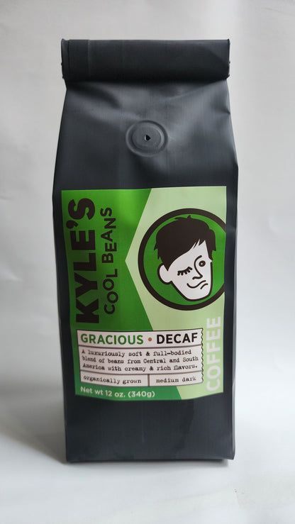 Kyle’s Cool Beans Gracious Decaf, Black bag with a green label, A luxuriously soft & full-bodied blend of beans from Central and South America with creamy & rich flavors. Organically grown. Medium dark. 