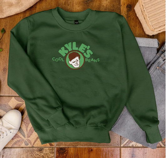 Green sweatshirt with 'Kyle's Cool Beans' logo on a wooden floor.