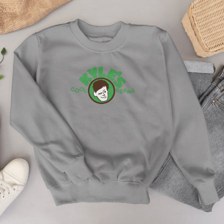 Gray sweatshirt with Kyle’s Cool Beans logo on a light gray surface